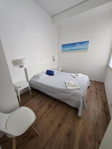 a white bedroom with a bed and a chair at Il Faro Trapani b&b Rooms & apartments in Trapani