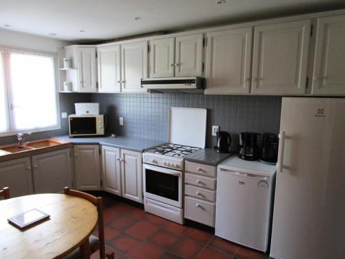 - une cuisine avec des placards blancs, une table et un réfrigérateur dans l'établissement Résidence 05023m-lacanau Ocean - Grande villa 5 chambres pour 12 personnes avec piscine privée, plage à pieds, Lacanau Océan MAE-0421, à Lacanau