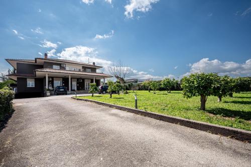 a house with a driveway in front of a field at - NumberZ - Rooms Apartments and Suites with Wi-Fi and AC in Borgo Isonzo