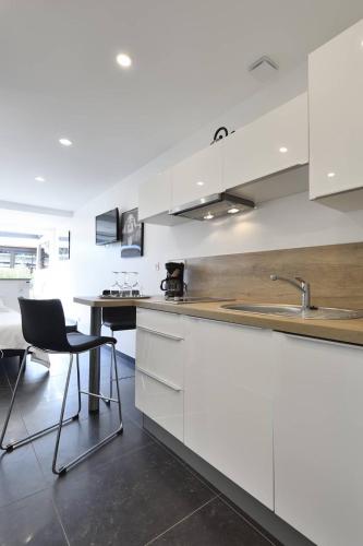 une cuisine avec des armoires blanches, une table et un évier dans l'établissement Studio POPPY - Port Nature 461 - Luxe - 2 personnes, au Cap d'Agde