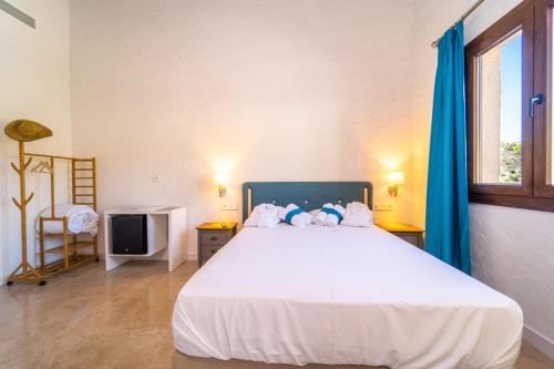 a bedroom with a large white bed with blue curtains at Hostal Foies de Baix in Relleu