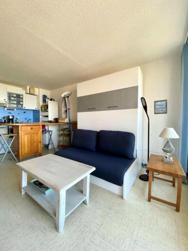 un salon avec un canapé bleu et une table dans l'établissement Résidence Les Cytises - Appartement vue mer pour 4 personnes à Lacanau Océan MAE-0671, à Lacanau
