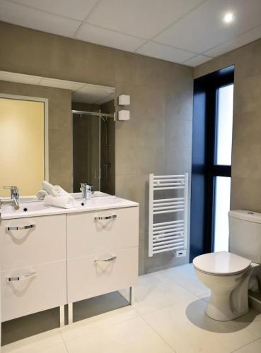 une salle de bain avec un lavabo blanc et des toilettes dans l'établissement Résidence Margalex - Maison mitoyenne dans belle résidence neuve, piscine collective à Lacanau Océan MAE-0681, à Lacanau