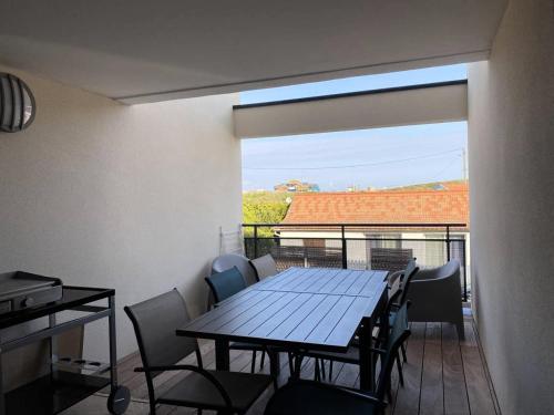 - une table à manger et des chaises dans une chambre avec balcon dans l'établissement Résidence Roof Top - Appartement T3 neuf pour l'accueil de 6 personnes à 70m des plages MAE-0851, à Lacanau