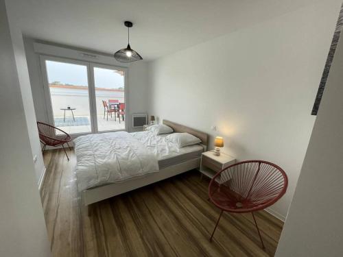 une chambre avec un lit et deux chaises et une fenêtre dans l'établissement Résidence Les Embruns - Appartement neuf à proximité des commodités pour 6 personnes avec parking MAE-0961, à Lacanau