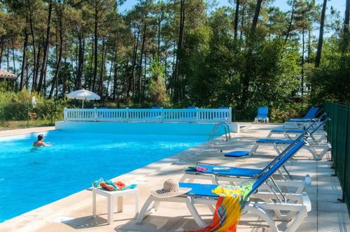 - une piscine avec des chaises et une personne dans l'eau dans l'établissement Résidence 04094-lacanau - Maison familiale dans un complexe au calme près du lac MAE-0971, à Lacanau