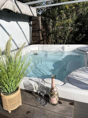 - un bain à remous avec 2 verres et une bouteille de vin dans l'établissement Résidence 05029-lacanau Ocean - Villa pour 9 personnes avec jardin et jacuzzi à Lacanau Océan MAE-1001, à Lacanau
