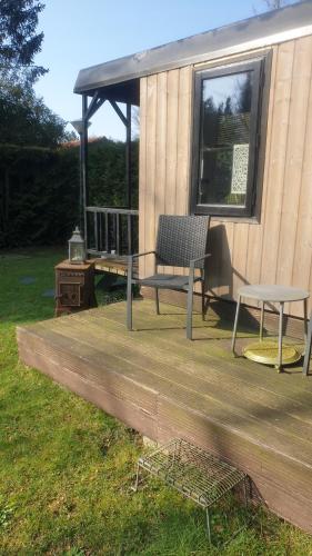 a bench and a table on a wooden deck at Pipowagen Bed bij Bos in Putten
