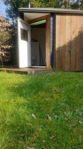 a building with a door open in a yard at Pipowagen Bed bij Bos in Putten