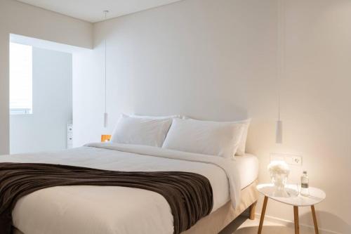 Un dormitorio con una gran cama blanca con una mesa. en 2bd Boho Sea View Apartment By The Olon, en Vari
