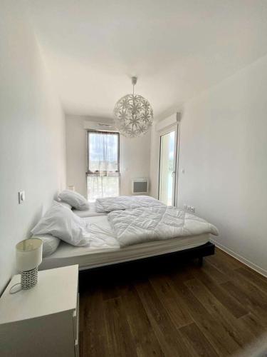 - un grand lit dans une chambre blanche dotée d'un lustre dans l'établissement Résidence Les Embruns - Appartement neuf à proximité des commodités pour 4 personnes avec parking MAE-9381, à Lacanau