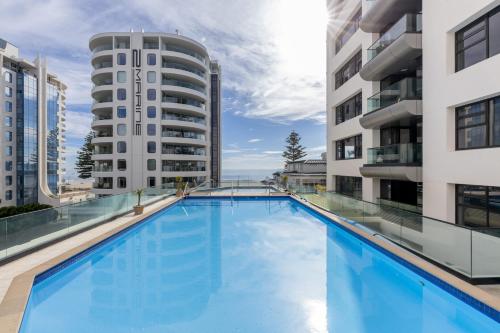 a large swimming pool in the middle of two buildings at Spectacular Sunrises & Sea Views - Pool Spa Gym in Mount Maunganui