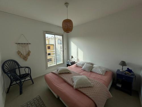 Un dormitorio con una cama y una silla y una ventana. en Le Syracuse, en Antibes