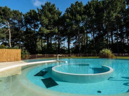 une grande piscine avec de l'eau bleue et des arbres dans l'établissement Résidence Lacanau Les Pins - Domaine du Golf - Appartement T2 dans résidence avec piscine collective chauffée MAE-8341, à Lacanau