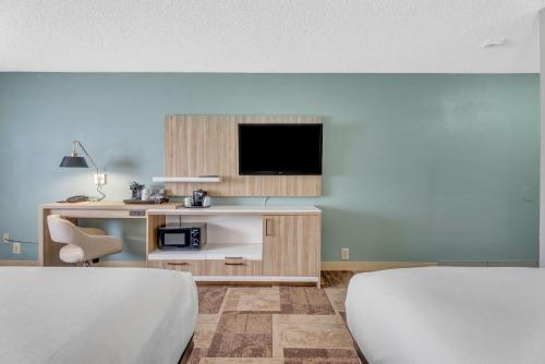 a room with two beds and a tv and a desk at Wyndham Garden Newark Fremont Silicon Valley in Newark