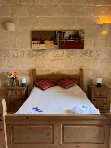 a bedroom with a wooden bed with two red pillows at Arkati house in Munxar
