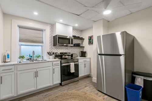 een keuken met witte kasten en een roestvrijstalen koelkast bij San Marco Villa Duplex w Backyard BBQ & Firepit in St. Augustine