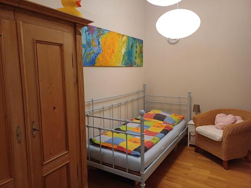 a bedroom with a crib and a chair and a painting at Tillyhome in Nürnberg