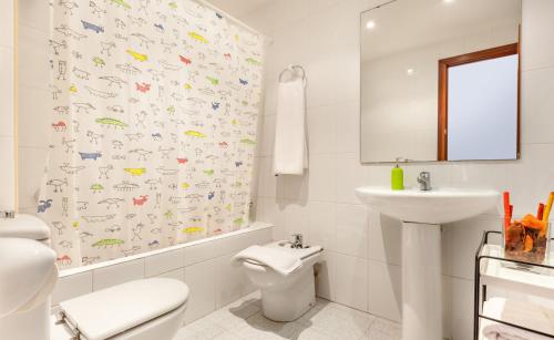 Baño blanco con aseo y lavamanos en Hola Sitges Apartments, en Sitges