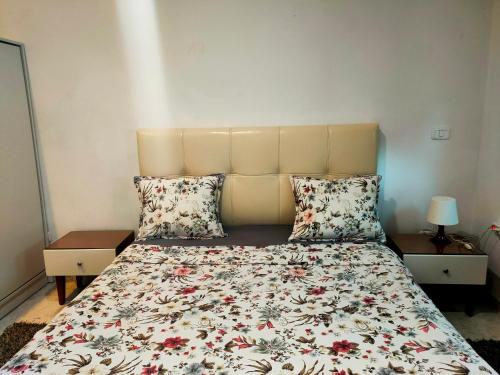 a bedroom with a bed with a floral bedspread and pillows at luxurious and cosy apartment close to tunsia mall lac 2 in El Aouina Station