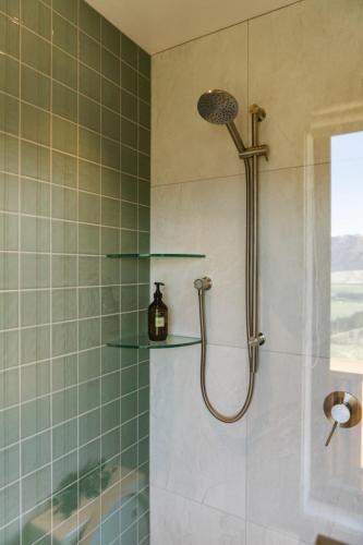 a shower with glass shelves in a bathroom at Snowgrass Hut - Above & Beyond in Mount Somers