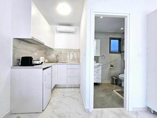 una cucina bianca con mobili bianchi e un lavello di Dream Luxury Apartment Suites a Pastida