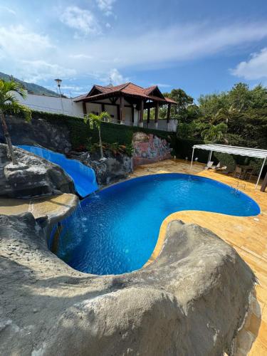 a swimming pool in a backyard with a large rock at VILLA ORION piscina y discoteca PRIVADA K18 in Cali