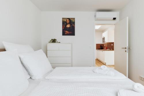 a white bedroom with white bedding and white cabinets at Symphony Apartments Vienna - Garden, Terrace and Grill in Vienna