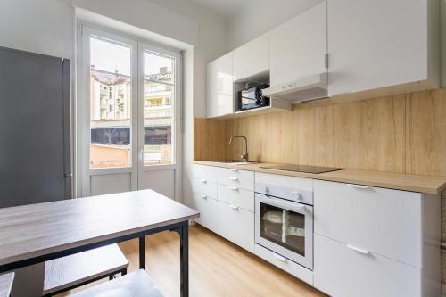 une cuisine avec des armoires blanches, une table et une fenêtre dans l'établissement Getaway to Strasbourg 6Travelers, à Strasbourg