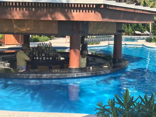 two people sitting at a bar in a pool at 2BD Grand Luxxe Villa Nuevo in Nuevo Vallarta 