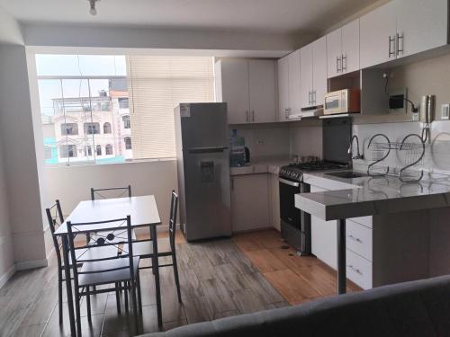 a kitchen with white cabinets and a table and chairs at Bonito departamento en cercado in Tacna