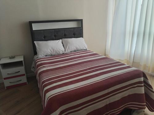 a bedroom with a large bed with a striped blanket at Bonito departamento en cercado in Tacna