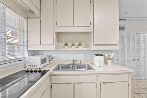 a white kitchen with a sink and a microwave at SUPER BOHO - At Lake Toho Fishing VINTaGE VIBEs in Kissimmee