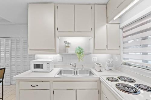 a white kitchen with a sink and a microwave at SUPER BOHO - Lake Toho Timeless Charm in Kissimmee