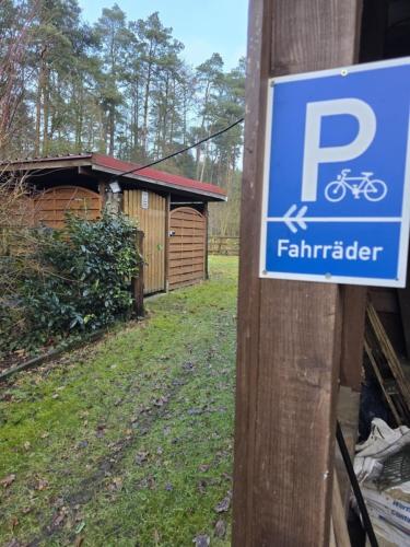 a sign on a wooden pole with a house with a bike sign at Ahauser Ferien- und Business-Appartement 29qm in Ahausen