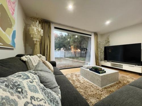 a living room with a couch and a large flat screen tv at California 'Luxe Boho' with Pool in Echuca