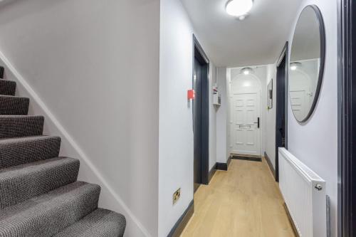 a hallway with a staircase with a round mirror at Ashton Getaway Sleeps 14 Free Parking in Dukinfield