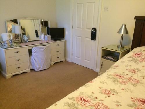 a bedroom with a bed and a dresser and a mirror at Ballacowell in Sulby