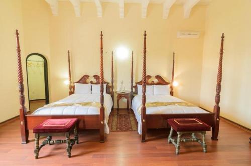 a bedroom with two beds and two stools at Hotel Castillo de Santa Cecilia in Guanajuato