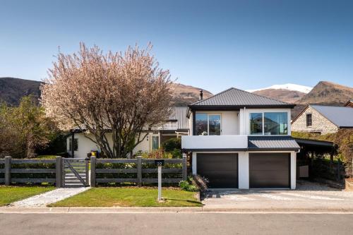 a house with a fence and a garage at Arrowtown Family Home with spa in Arrowtown