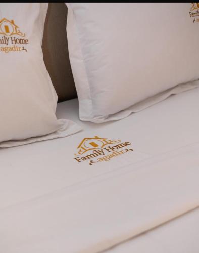 a bed with a white pillow and a sign on it at FAMiLY HOME in Agadir