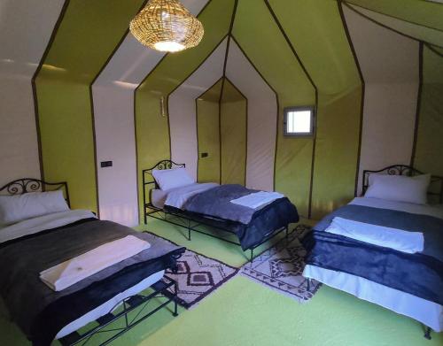 a room with two beds and a chandelier at Magic Carpet camp in Merzouga