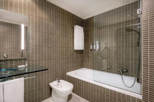 a bathroom with a tub and a toilet and a sink at AC Hotel Firenze by Marriott in Florence