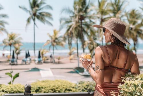 a woman in a brown dress and hat holding a wine glass at Paradise Jaco Beach Front in Jacó