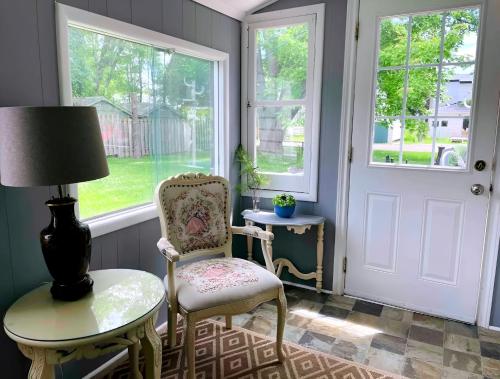 a room with a chair and a table and windows at Charming Cottage in Wellington's Heart near Beach in Wellington