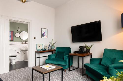 a living room with two green chairs and a flat screen tv at Kimpton Clocktower by IHG in Manchester