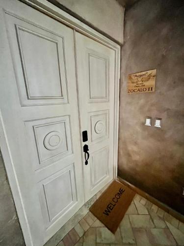 a white door with a welcome sign next to it at Val'quirico Auguri Zócalo II, Depto 5 Camas in Santeagueda