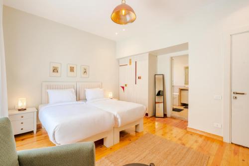 a white bedroom with a large bed and a chair at Longchamps l Zamalek l Boutique Hotel with Breakfast in Cairo