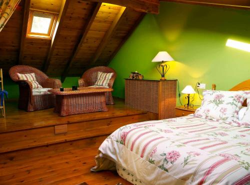 a bedroom with green walls and a bed and wicker chairs at Casa Rural O Carreiro in Cedeira