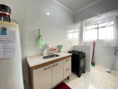 a kitchen with a sink and a stove at Kit dos Sonhos – Frente Mar na Tupi! in Samaritá